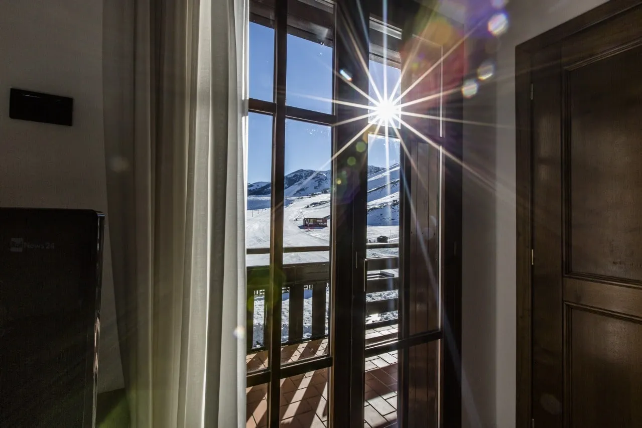 Sole e piste innevate dal balcone di una camera di Hotel Pizzalto